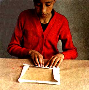 Imagen de una nia colocando una hoja de papel sobre una tabla de madera
