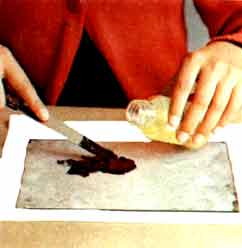 Imagen de una persona que se ayuda de una esptula y de un poco de aceite para repartir la pintura