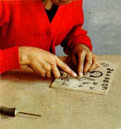 Imagen de una nia haciendo el grabado sobre la madera