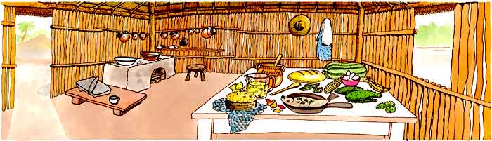 En esta imagen vemos una cocina en una casa hecha de palma. Hay un fogón, con ollas de barro, en el piso un metate. También se ve una mesa llena de frutas, verduras, peces, pan, tortillas.